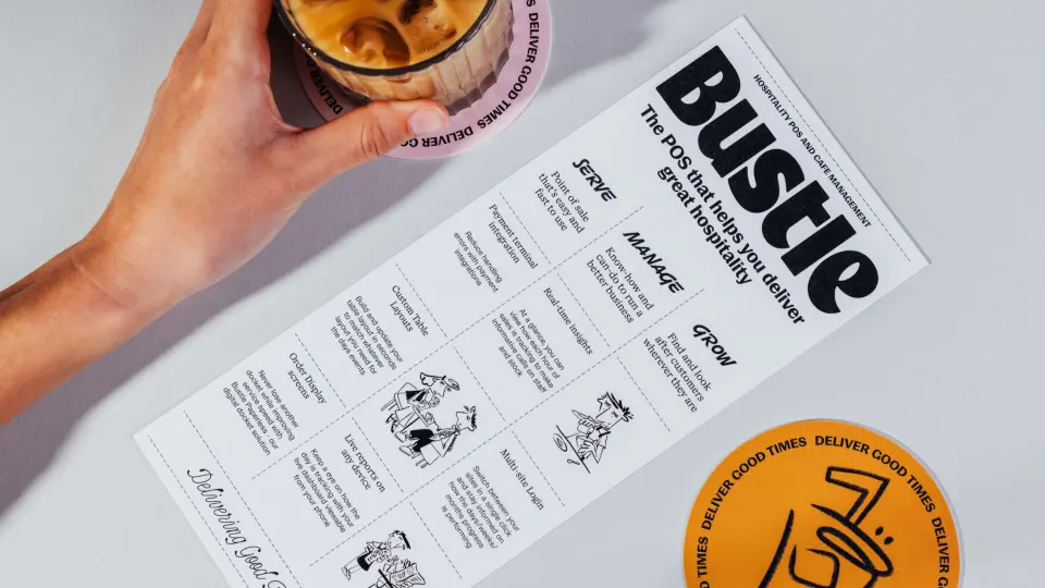Hand holding a Bustle-branded printed menu next to a drink