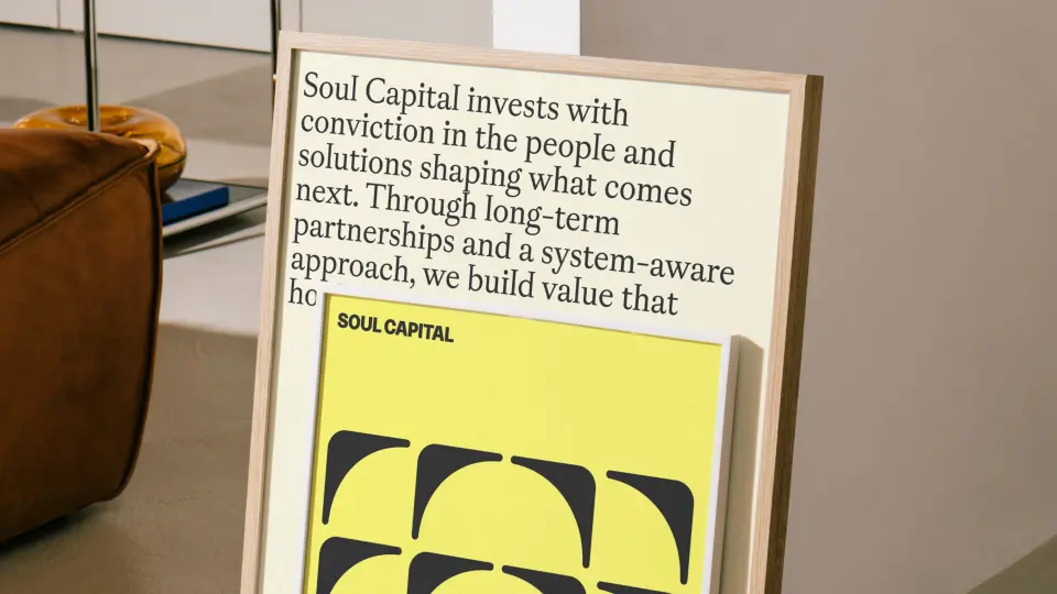 Printed leaflet held up in front of a yellow graphic poster