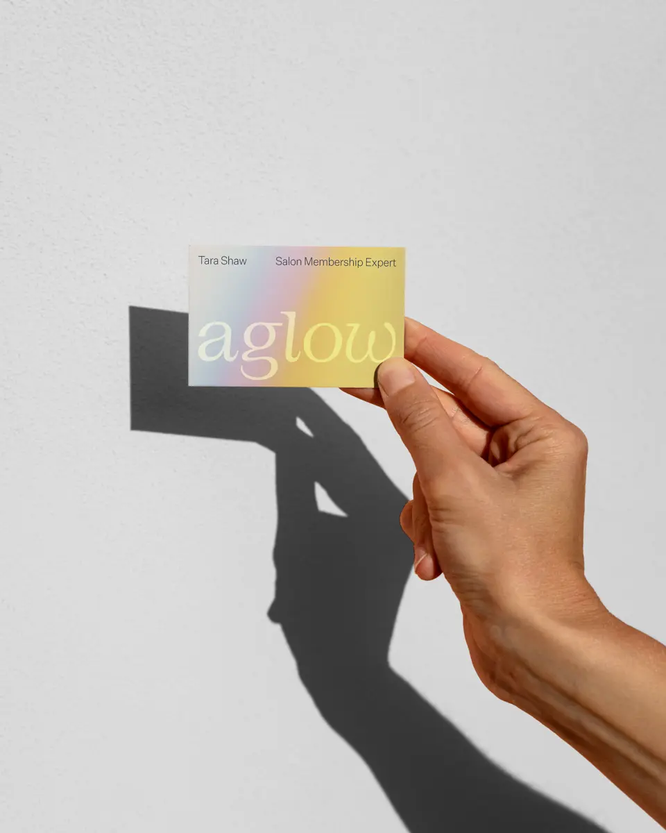 Hand holding an aglow card, casting a shadow on a grey wall