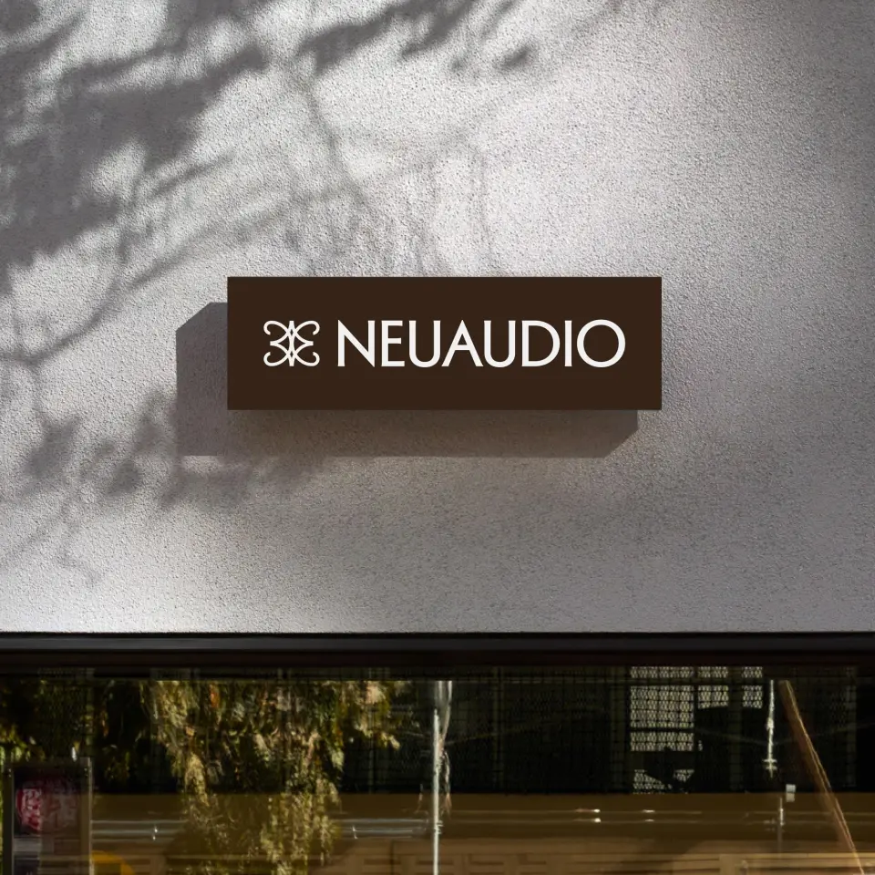 NeuAudio sign on a building with tree shadows