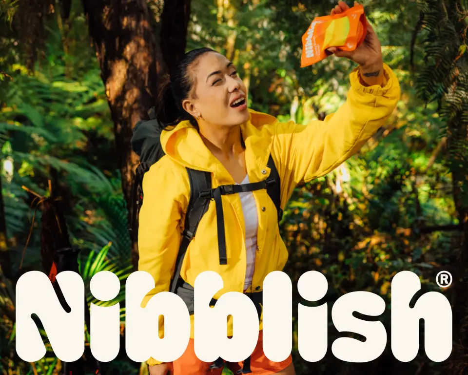 Person in a yellow jacket smiling in a forest above the Nibblish wordmark
