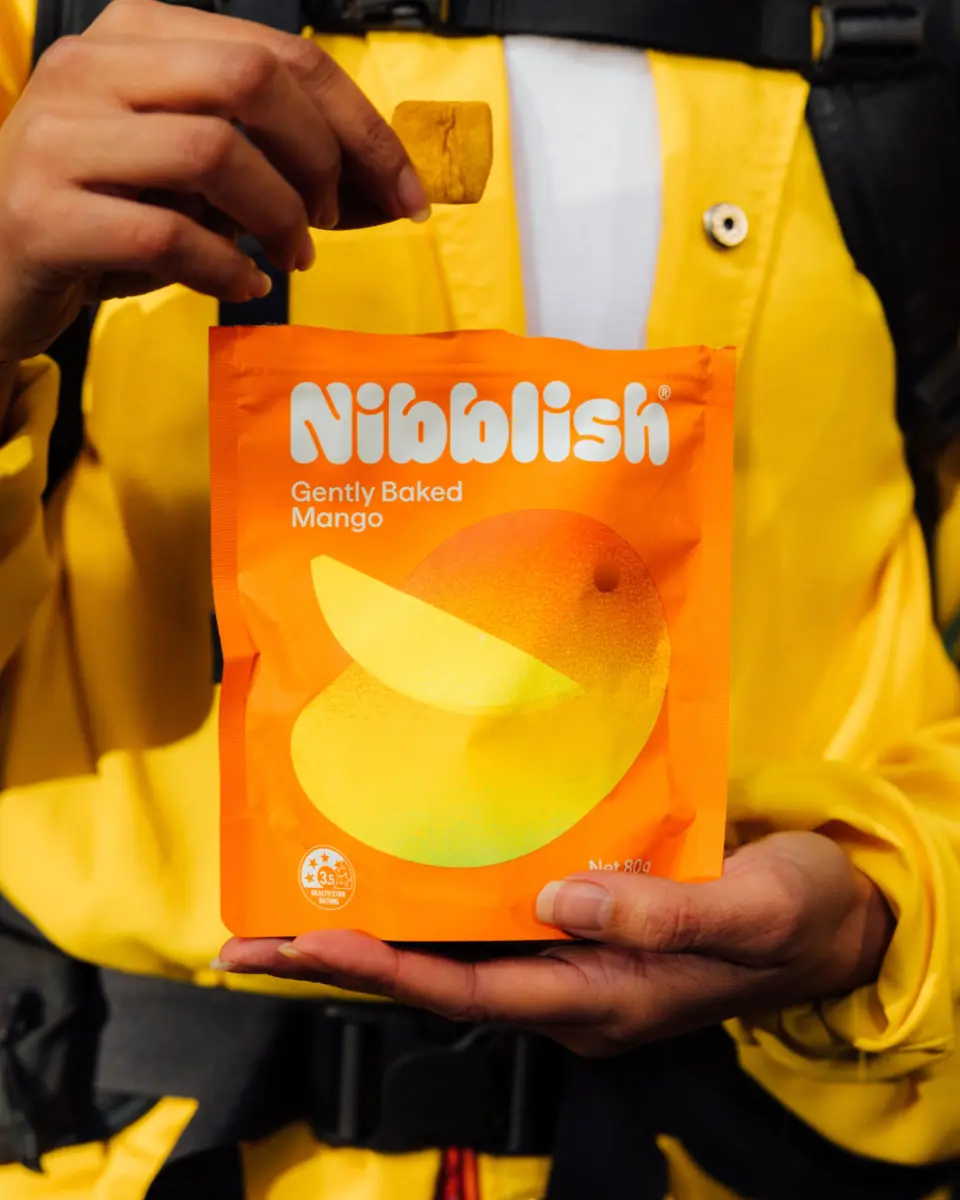 Person in a yellow jacket holding an orange Nibblish pouch