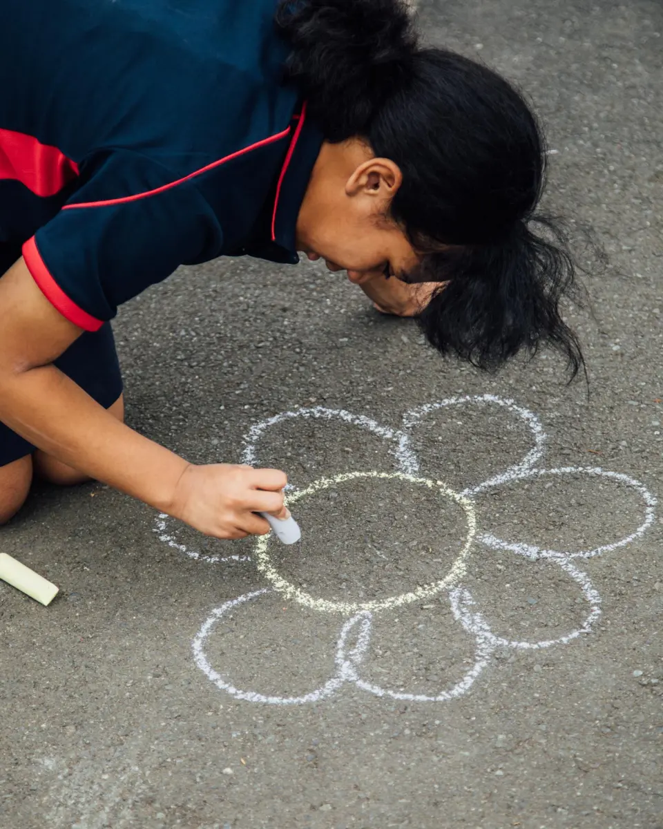 Child chalking a flower shape on a playground