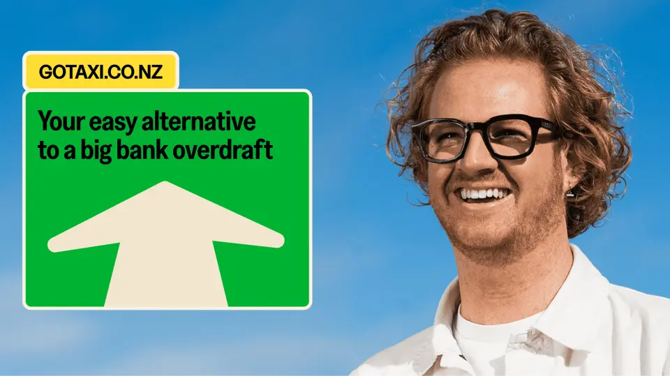 Smiling man in glasses beside a Taxi poster with an arrow