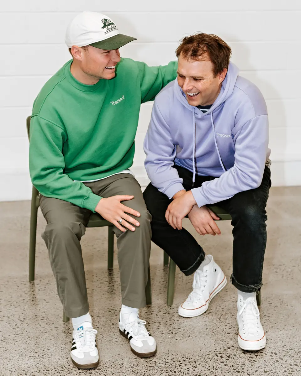 Two men sitting together in sweatshirts, smiling