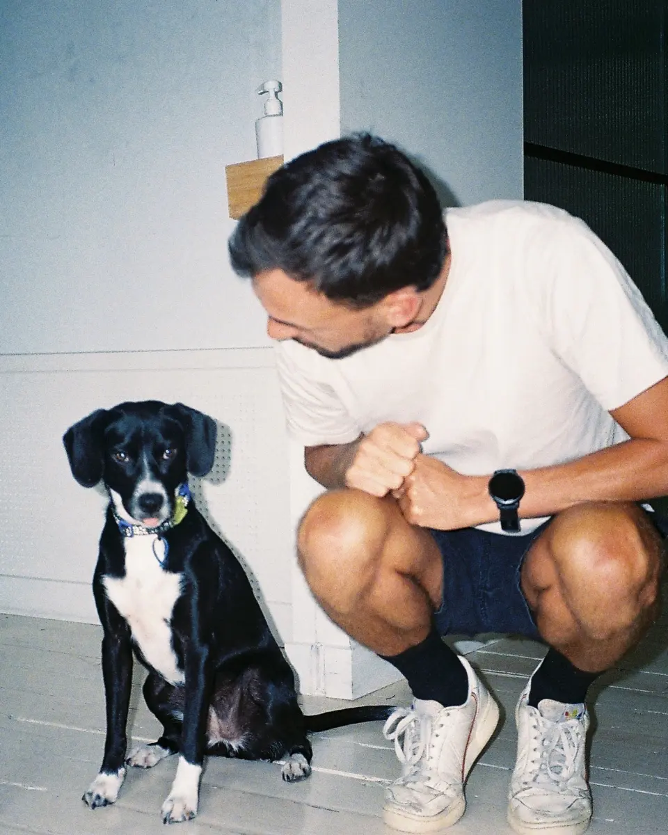 Man crouching next to a black and white dog