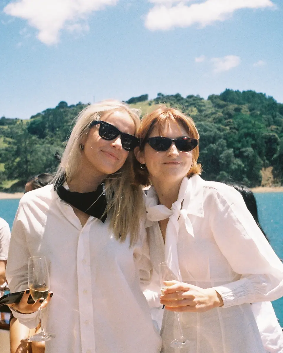 Two women in sunglasses smiling by the water